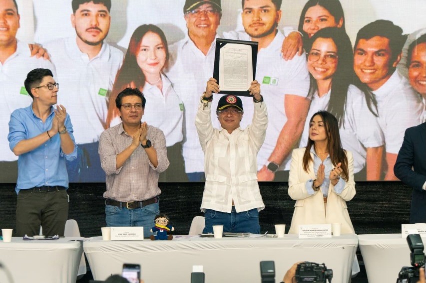 Acto de promulgación: el presidente Gustavo Petro sostiene el documento de la reforma financiera a la Ley 30, junto a asistentes.